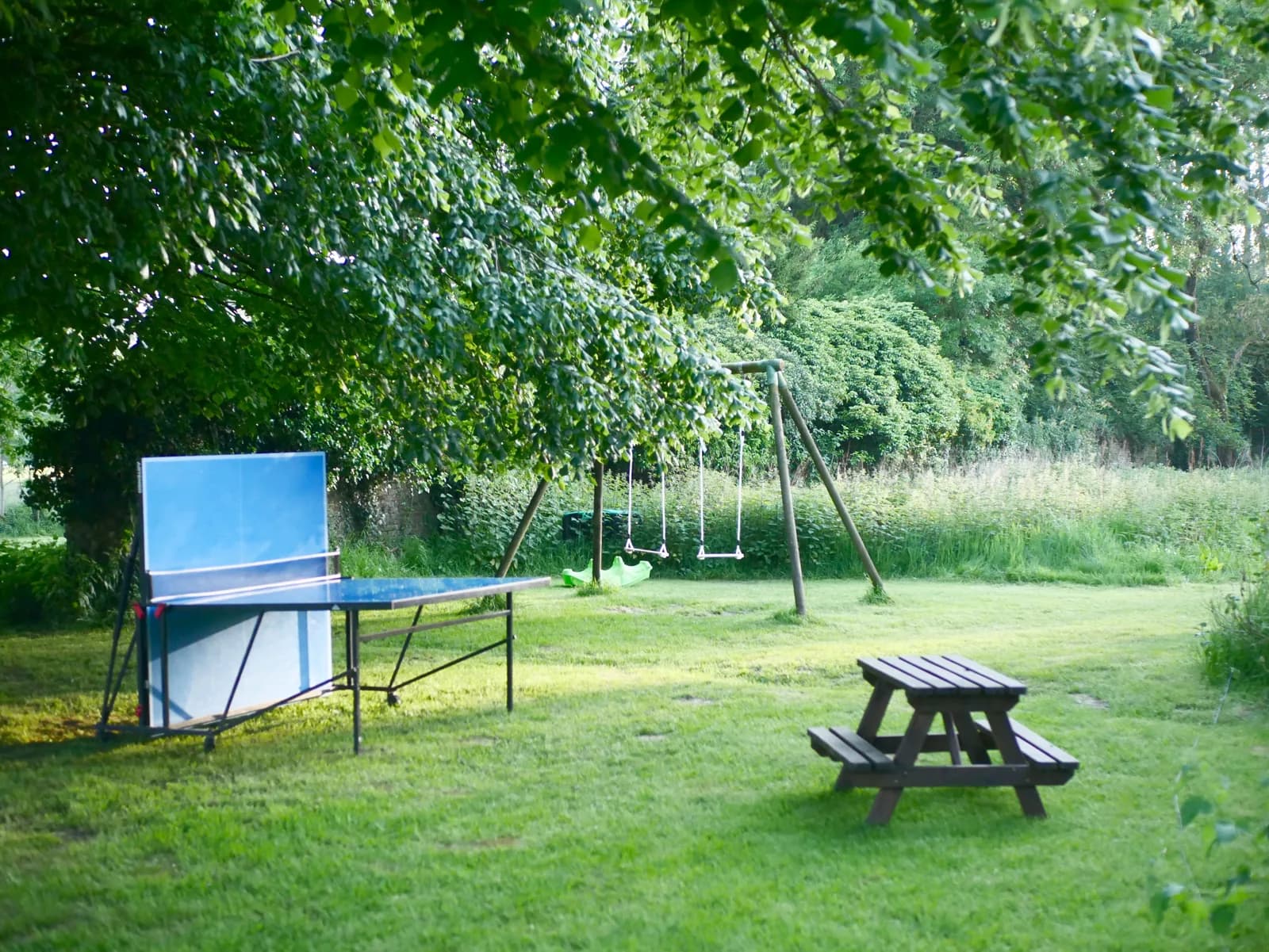 Table de ping-pong et balançoires dans le jardin